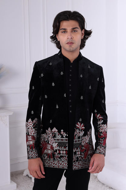 Man wearing a black embroidered jacket in a white room