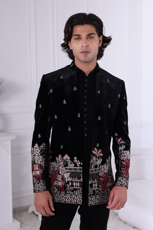 Man wearing a black embroidered jacket in a white room